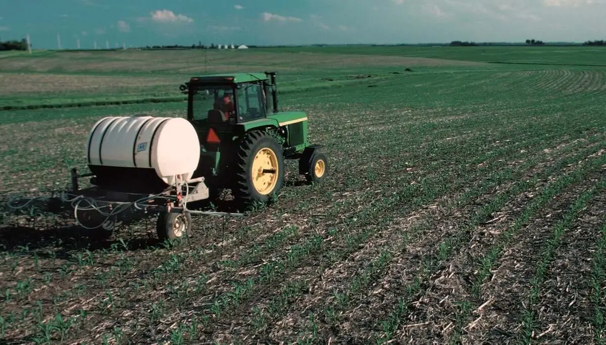 farmer applying fertilizer to a corn field https://greener4life.com/blog/fertilizers-advantages-and-disadvantages